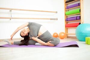 joven mujer es haciendo gimnasia en gimnasia. sano estilo de vida. púrpura estera foto