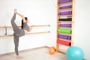 joven mujer es haciendo gimnasia en gimnasia. sano estilo de vida. pierna arriba foto