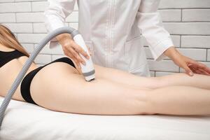 cosmetologist does RF lifting of thigh, radio waves, removal of cellulite. beautiful slim model photo