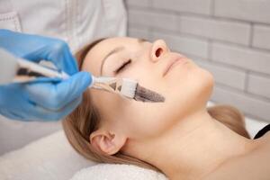 cosmetologist does procedure of carbon peeling of face. Black mask, laser skin cleansing. Modern treatments. beautiful skin photo