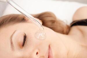 cosmetologist does procedure of facial cleansing, massage, rejuvenation, vacuum. photo