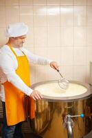 man makes cheese, boils milk in cistern, heating, temperature. Milk folding process, home production, business, individual entrepreneur. tile. photo