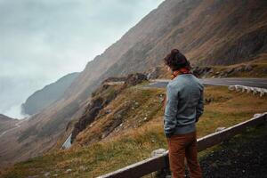 man stands on road in mountains in Romania, Carpathians. concept of loneliness, freedom, melancholy and thoughtfulness. Autumn, rain and fog, nature, outdoors. Man and nature, landscape, background photo