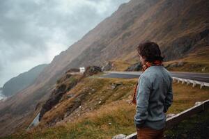 man stands on road in mountains in Romania, Carpathians. concept of loneliness, freedom, melancholy and thoughtfulness. Autumn, rain and fog, nature, outdoors. Man and nature, landscape, cold. photo