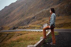 man stands on road in mountains in Romania, Carpathians. concept of loneliness, freedom, melancholy and thoughtfulness. Autumn, rain and fog, nature, outdoors. Man and nature, landscape, sweater. photo