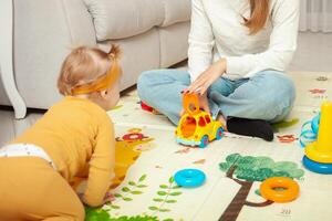 Mother and daughter play together, learn, home room, fun, love and care. A one year old girl. car. photo