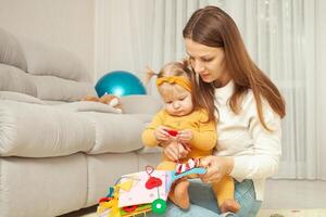 Mother and daughter play together, learn, home room, fun, love and care. A one year old girl. soft book. photo