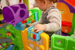 A small two-year-old girl plays with toys in the playroom photo