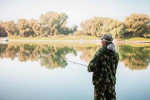 senior concept. A fisherman on river catches predatory fish. Useful hobby, beautiful autumn, active healthy lifestyle. photo