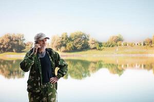 pensioner talks on phone on vacation, fisherman, Internet in nature, communication with friends, relatives. copy space photo