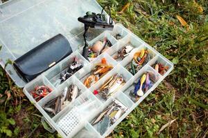 Fishing gear in organizer, box. Various baits for predatory fish. Artificial fish for hook. Weights. Fishing hobbies, outdoor. Multicolored photo