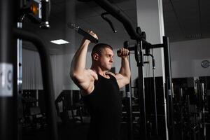 retrato de un atleta, un Deportes hombre entrenador lo hace un ejercicio en simulador en el gimnasia. sano activo estilo de vida, batidos músculos. grave foto