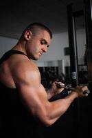 retrato de un atleta, un Deportes hombre entrenador lo hace un ejercicio en simulador en el gimnasia. sano activo estilo de vida, batidos músculos. mano foto