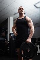 Portrait of a handsome man in gym. Coach, athlete, bodybuilder, muscular sexy body, darkness. serious photo