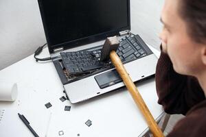 hombre destruido ordenador portátil con un martillo. nervioso trabajar, calesa computadora, errores, lento Internet, no salvado en el juego, impreso texto, colgado. malo antiguo computadora fallido, lo hace no giro en, foto