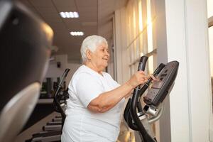 An elderly pensioner plays sports in the gym photo