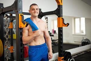 un muscular entrenador en gimnasio es comprometido en Deportes en simuladores. capacitación, entrenamiento, peso pérdida programa. el hombre en simuladores. Copiar espacio, interior concepto, sano activo estilo de vida. sonriente, contento foto