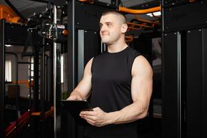 young handsome coach with a tablet in his hands. Coaching, individual courses of sports and weight loss. Modern technology, records the results, social network, Internet. portrait photo