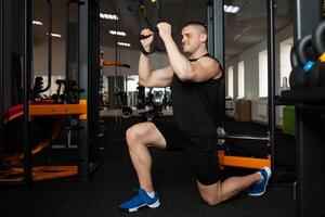 A beautiful trainer performs exercises on simulator, squats, push-ups on weight, muscular body. Athlete in the gym, coaching, individual weight loss courses, sports, advertising. Smiling photo