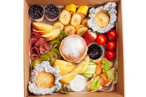 Gastronomic box, food, home delivery of ready meals. Food for holiday, dinner, corporate. Catering. A set of pancakes, buns, fruit and breakfast food photo