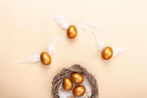 vacío espacio para texto, un bandera de contento Pascua de Resurrección. pintado dorado huevos, blanco plumas. Copiar espacio plano laico parte superior ver huevos con alas mosca lejos desde el nido foto