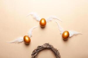 Empty space for text, a banner of happy Easter. Painted golden eggs, white feathers. copy space flat lay top view eggs with wings fly away from the nest photo