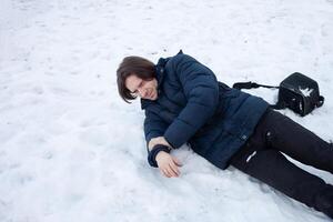 un hombre caídas en el nieve. el hombre resbaló y estaba herido. que cae en hielo. invierno. fractura, moretón, dislocación. foto