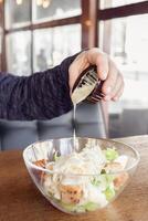 Delicious salad with croutons, grilled chicken breast, grated parmesan cheese and cos lettuce in the gravy boat, simply and healthy recipe, horizontal top view A man pours sauce photo