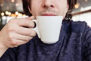 un hombre bebidas café en un cafetería, un restaurante. interior, natural luz de sol, borroso fondo, oblicuo. bocadillo, desayuno. almuerzo descanso. foto