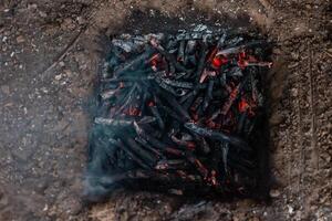 Coals from a campfire in a sand pit. photo