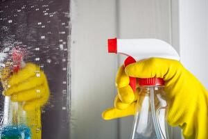 Maid with rubber glove cleaning tap and sink. photo
