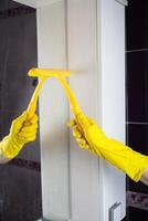 Maid with rubber glove cleaning tap and sink. photo