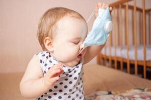 The child does not want to wear a medical mask. One year old girl photo