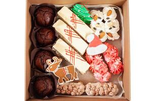 Gift box for Christmas. Delivery of food to the house for the New Year. Gingerbread, muffins and cakes. A deer, a tree and Santa's hat. photo