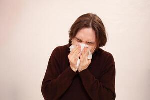 A man sneezes, a medical mask. Empty space for text on a white background. A sick man in home quarantine. Coronavirus photo