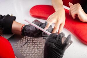 The manicurist holds hands of the client in beauty salon on desktop for manicure with nail polishes, napkins, creams and lighting instruments photo