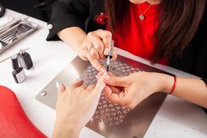 The manicurist holds hands of the client in beauty salon on desktop for manicure with nail polishes, napkins, creams and lighting instruments photo