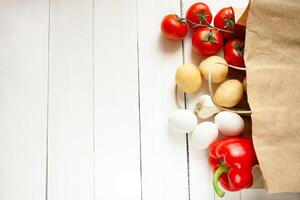 Paper bag on a wooden background, vegetables from the store photo