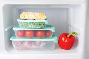 Frozen vegetables and meat in blue plastic containers photo