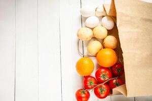 Paper bag on a wooden background, vegetables from the store photo