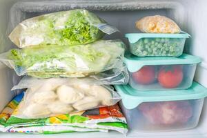 Frozen vegetables and meat in blue plastic containers photo