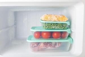 Frozen vegetables and meat in blue plastic containers photo