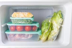 Frozen vegetables and meat in blue plastic containers photo