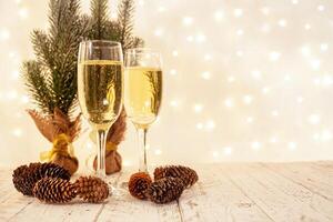 glasses of champagne on a wooden table. The background with a blurred golden garland, sideways. Christmas decorations, background for postcards and congratulations on the New Year. photo