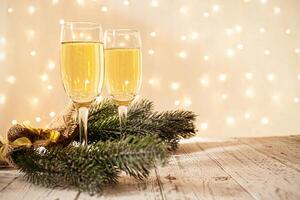 glasses of champagne on a wooden table. The background with a blurred golden garland, sideways. Christmas decorations, background for postcards and congratulations on the New Year. photo