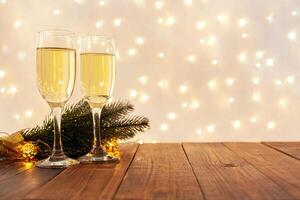 glasses of champagne on a wooden table. The background with a blurred golden garland, sideways. Christmas decorations, background for postcards and congratulations on the New Year. photo