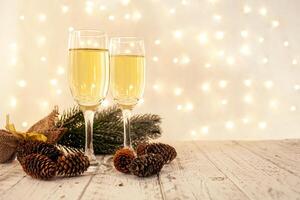 glasses of champagne on a wooden table. The background with a blurred golden garland, sideways. Christmas decorations, background for postcards and congratulations on the New Year. photo