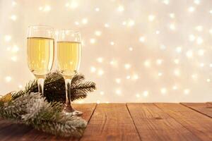 glasses of champagne on a wooden table. The background with a blurred golden garland, sideways. Christmas decorations, background for postcards and congratulations on the New Year. photo