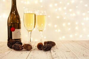 glasses of champagne on a wooden table. The background with a blurred golden garland, sideways. Christmas decorations, background for postcards and congratulations on the New Year. photo