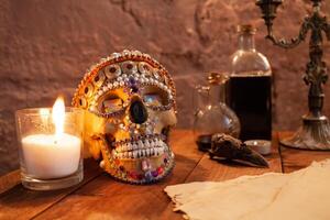 Photo zone in the studio for Halloween. Dramatic scenery for All Saints Day celebrations. The skull is decorated with beads and stones, candles, ink, crow's skull, old parchment on atable.